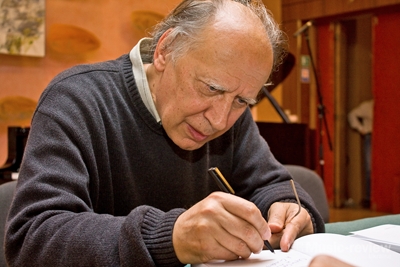 Композитор Валентин Сільвестров, що зосереджено залишає автограф на власній книзі